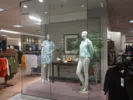 A Dillards clothes demo case, with two manequins wearing blue shirts