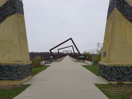 A picture of the High Trestle Trail Bridge in Madrid, IA at the enterance. Two tall stone pillars are at the sides of the picture.