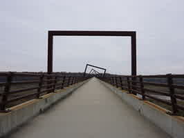 A picture of the High Trestle Trail Bridge, further down the bridge. Rectangular arches line the bridge, changing rotation in a clockwise pattern.
