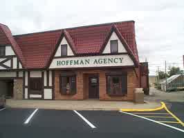 The Hoffman Agency building in Schleswig, IA. Brown brick is used for the bottom half, with the upper half using cream walls and dark brown boards.