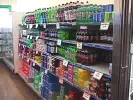 The soda aisle at a grocery store, with large bottles and 12-packs of soda.