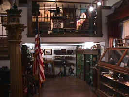 An antiques store. Cabinets and shelves house small collectibles, while larger collectibles are on the floor.