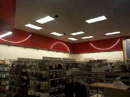 White half-circle neon in the mall's Target. The neon is against red drywall, shown above the men's clothing department.
