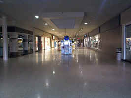 The northeast wing of the mall, looking into the mall. To the sides are a mix of empty and open stores, with a photo booth in the middle of the hall.