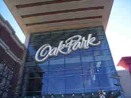 The front entrance to the Oak Park Mall. The mall's cursive logo sits over the glass front of the building.