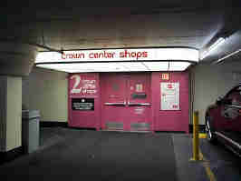 The parking garage entrance to the Crown Center Shops. The doors and the entrance surrounding them are painted pink, with a large awning of light over the entryway.