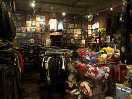 The back of the Zona Rosa Hot Topic. The walls are lined with shirts, pants, and little trinkets. The middle of the store has racks and shelves for t-shirts, plushies, and other merch.