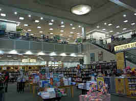 A normally lit photo of the Barnes & Noble. Tables support board games and other merch in the middle, with shelves of books in the background.