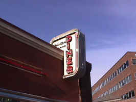 The sign for the Philips Avenue Diner. "Philips Avenue" is written in cursive, and "DINER" is spelt vertically in neon. A neon border surrounds the sign.