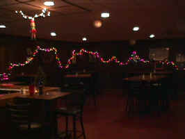 An under-exposed picture of a dining room in the Spink Family Restaurant. While it's hard to see, tables and chairs sit in the middle, with string lights hanging on the walls.