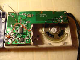 The back of the front of the radio. Taking up most of the space is the circuit board, sparsely populated with components. Visible in the bottom right is the speaker.